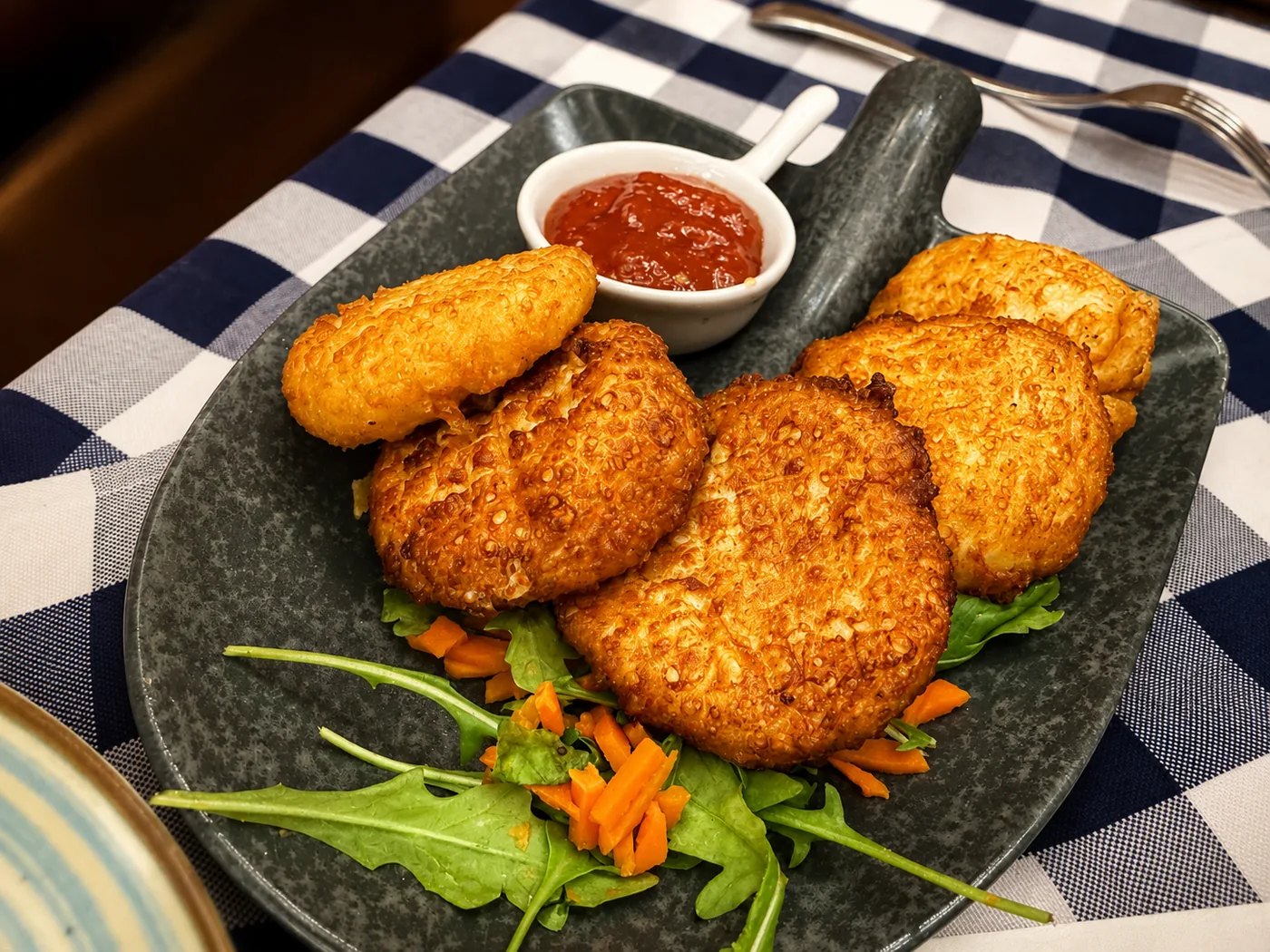 Warme Käse-Spezialität: Kross gebackene Käsehäppchen mit fruchtigem Dip und frischem Grün.